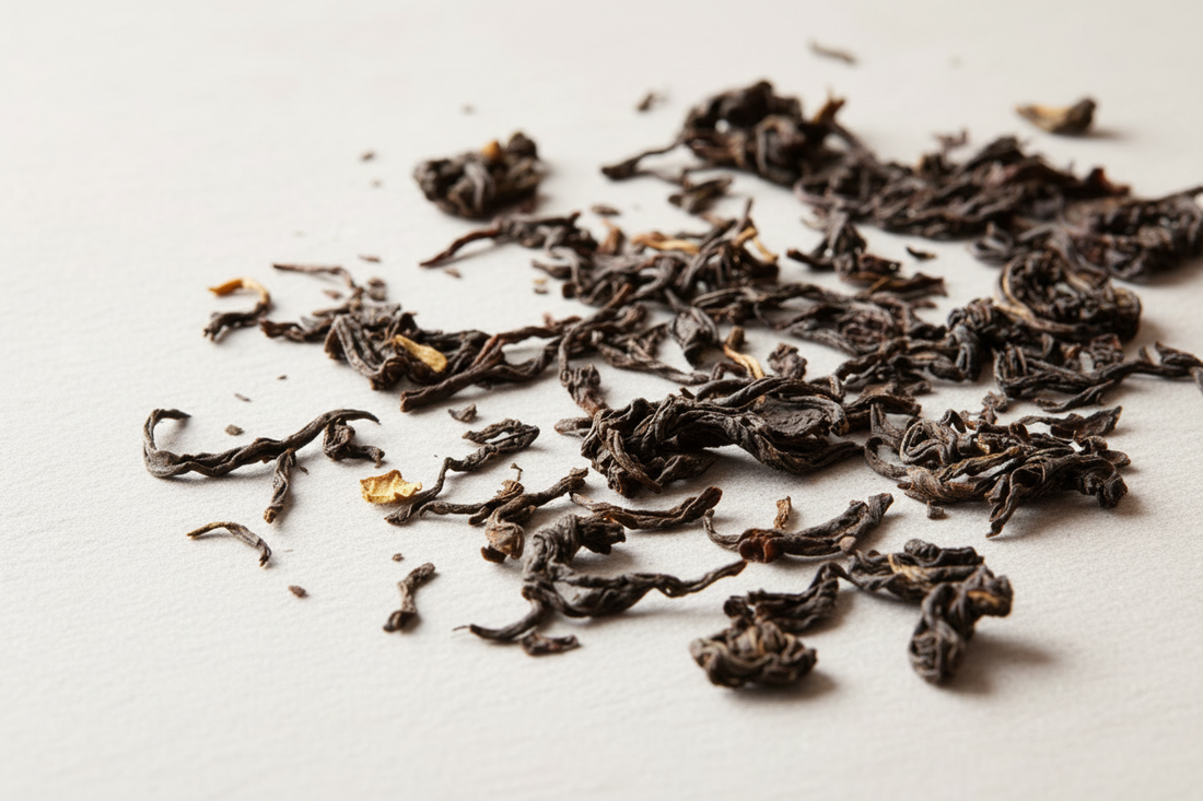 Loose leaf black tea leaves spread on a light surface, showing the texture and color of oxidized tea