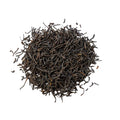 A pile of black wiry tea leaves on a white backgrouind.