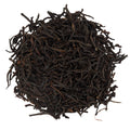 Close-up of dark brown dried Scottish Breakfast tea leaves on a white background