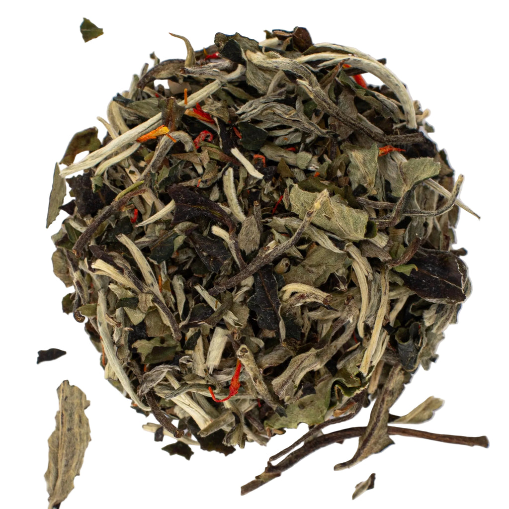 White tea leaves on a white background with specks of safflower blossoms
