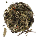 White tea leaves on a white background with specks of safflower blossoms